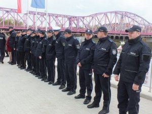 Policjanci stoją w szyku, w tle most na Odrze