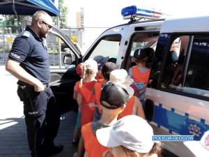 Dni otwarte u głogowskich policjantów - policjant z dziećmi przy radiowozie