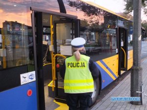 Policjantka stoi przy autobusie komunikacji miejskiej
