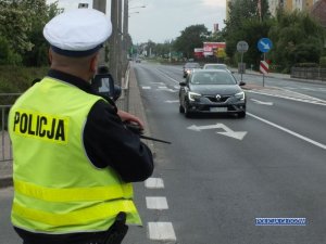 Policjant prowadzi pomiar prędkości pojazdu na drodze