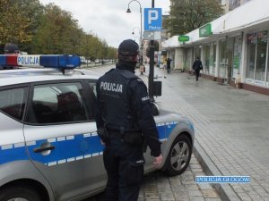 Policyjny patrol policjantów stoi przy radiowozie w centrum miasta w trakcie służby