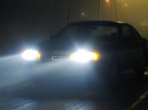 Pojazd na drodze we mgle z włączonymi światłami