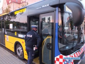Policjant ruchu drogowego kontroluje autobus komunikacji miejskiej