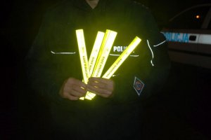 odblaskowe opaski widoczne w rękach policjanta oświetlone w porze nocnej.