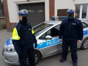 Policjanci z Wydziału Ruchu Drogowego na tle radiowozu oznakowanego